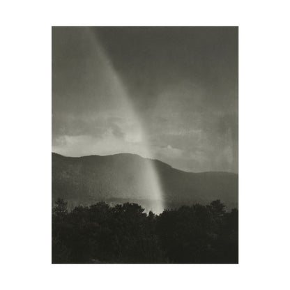 Black-and-white photograph of a rainbow illuminating dark mountains.