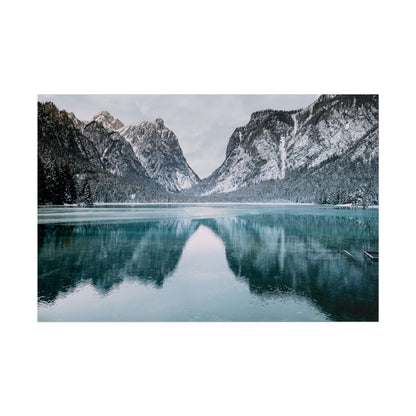 Winter landscape of mountains and lake reflecting in calm waters.